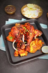 Tandoori chicken is a popular roast chicken recipe from India. Tandoor is a traditional wood oven. Chicken Tandoori Platter is served in a brass plate with salad and spices. Copy Space.