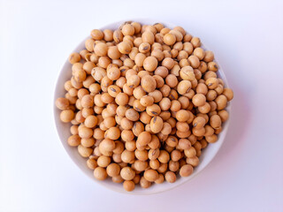 Dried Glycine max or soybean or soyabean, inside a white plate, isolated in white background