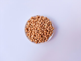 Dried Glycine max or soybean or soyabean, inside a white plate, isolated in white background