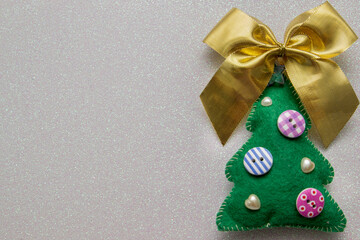 Homemade Christmas tree made of felt with bow on white glitter background