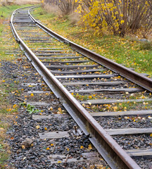 Vertical photo of a wooden old railway tracks and green grass. Train and transportation concept