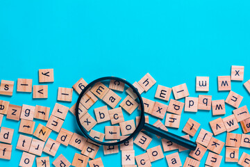 English alphabet made of square wooden tiles with the English alphabet scattered on blue background. The concept of thinking development,grammar.