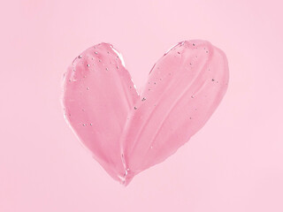 Liquid gel cosmetic smudge texture in heart shape on pink background. Aesthetic beautiful textured...