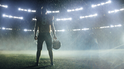 American Football Staduim: Lonely Athlete Warrior Standing on a Field Holds his Helmet and Ready to...