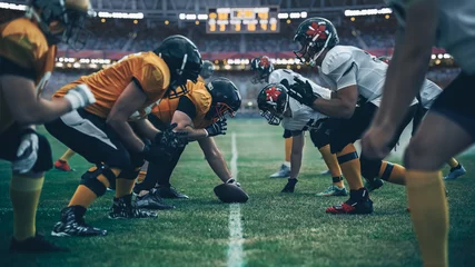 Zelfklevend Fotobehang American Football Championship. Teams Ready: Professional Players, Aggressive Face-off, Ready for Pushing, Tackling. Competition Full of Brutal Energy, Power. Stadium Shot with Dramatic Light © Gorodenkoff