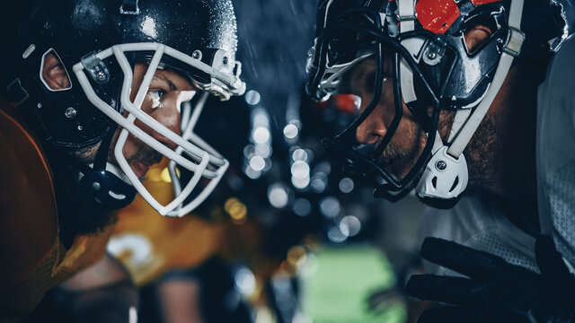 American Football Game Start Teams Ready: Close-up Portrait of Two Professional Players, Aggressive Face-off. Competition Full of Brutal Energy, Power, Skill. Rainy Night with Dramatic Light