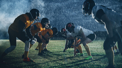American Football Field Two Teams Face-off. Players Ready to Start Run, Attack, Score Touchdown Points. Rainy Night with Athlete Silhouettes Preparing for a Fight for the Ball in Dramatic Fog