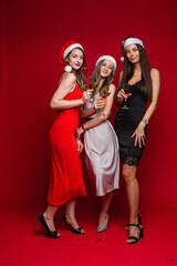 three cheerful female friends in beautiful dresses celebrate new year and rejoices together