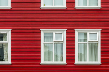 Fototapeta premium Windows on a red painted wall, colorful house, architecture detail in Reykjavik, Iceland