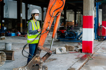 Fototapeta premium PORTRAIT, an Asian female engineer Wear a reflective vest and a white safety hat. Checking the machines at work construction site area