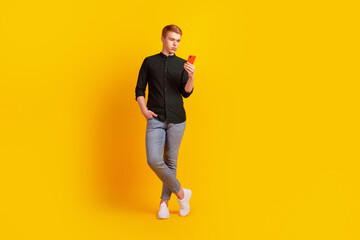 Fototapeta na wymiar Full size photo of young man look read chat type sms smartphone isolated over yellow color background