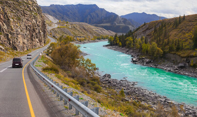 cars move along a mountain road along a mountain river and rocks. fuzzy focus