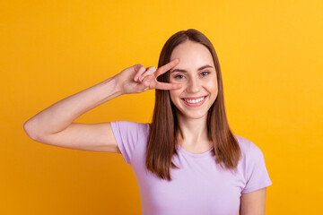 Photo of young cheerful girl have fun show fingers peace cool v-symbol isolated over yellow color background
