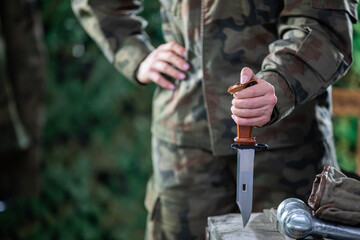 A woman in moro garb stabs a knife into a wooden crate. The soldier's equipment.
