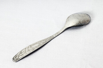 upside down teaspoon on white fabric background, close-up