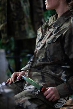 A soldier in a moro uniform sits on a chair with a bayonet in his hand. Strong women in the military.