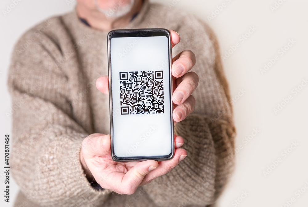 Wall mural Adult man holding a smartphone with a QR-code. Virtual immunity passport or international certificate of vaccination. Contactless payment. Close-up