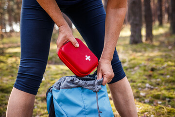 Woman taking out first aid kit from backpack. Prepared for health problems during hiking. Travel...