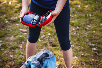 Woman opening first aid kit outdoors. Prepared for health problems during hiking. Travel insurance...