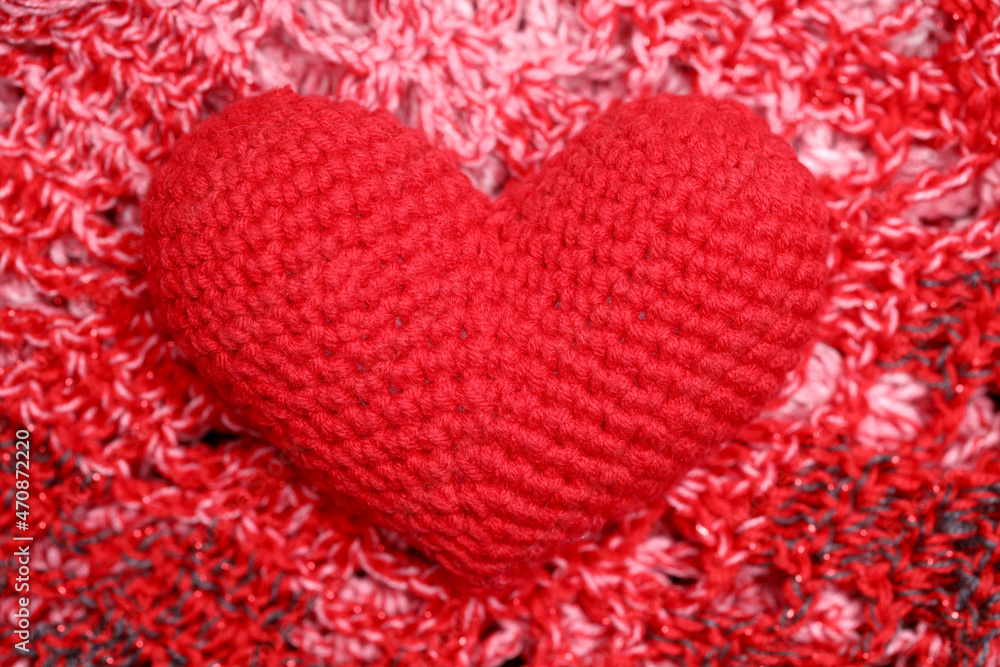 Poster knitted red heart lies on a red knitted background