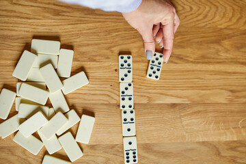 Top view of woman hand play white domino games on wooden table background with copy space, board...
