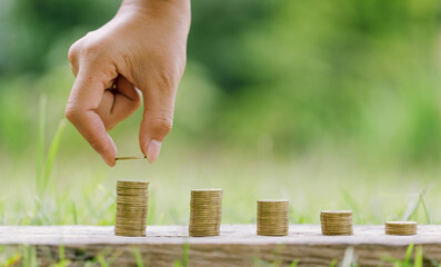 hand put money coins to stack of coins. Invest your money to get in come,growing business and future concept