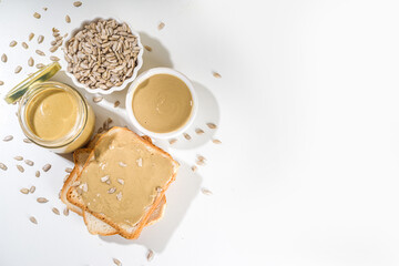 Sunflower seeds butter in small bow, jar and spoon. Modern alternative nut paste