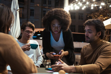 Confident young people working with their gadgets while sitting at the urban cafe