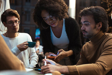 Woman looking at the smartphone and discussing something with smile while her coworkers