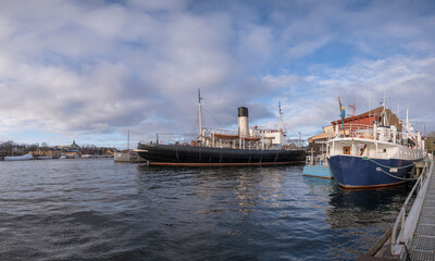 Fototapeta premium Autumn harbor view with different museum boats at a jetty in Stockholm
