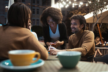 Four young people discussing something and laughing while sitting at the cafe