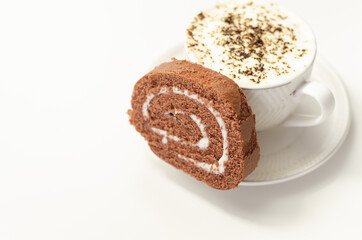 Chocolate sponge roll with a vanilla flavour filling and fresh coffee in the cup, chocolate swiss roll