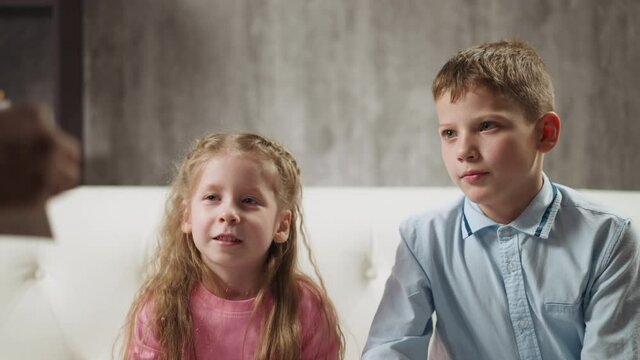 Attentive little siblings look at cards shown by African-American native speaker teacher and pronounce word at lesson checking knowledge slow motion