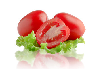 Two whole tomatoes and half on a lettuce leaf. Isolated on white background.