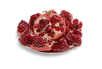 Half and pieces of peeled pomegranate on a plate isolated on a white background.