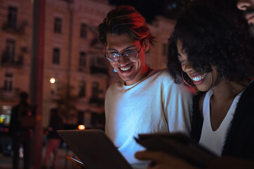 Man smiling toothy and looking at the laptop screen while his colleagues sitting nearby