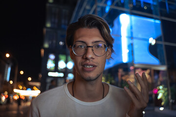 Man wearing glasses telling something to the camera emotionally while standing