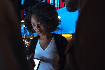 People looking at the tablet device while standing at the night urban settings