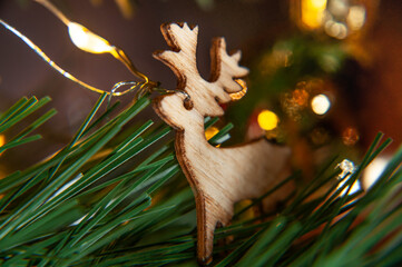 Christmas de-focused decorated tree with wooden garland. A garland element. A pine stick with close up little wooden deer.