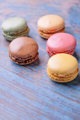 Stacked macarons of different flavors on an old wooden table.