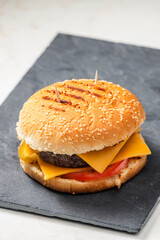 still life of cheeseburger on black plate
