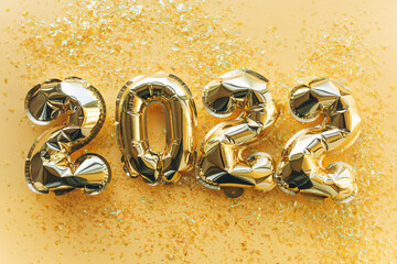 Balloons made of gold foil with the numbers 2022 on a gold background. Celebrating Christmas, New Years and holiday concept. 