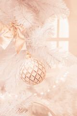 Christmas ball, festive decoration on white Christmas tree. Abstract cozy light coral background, trendy color