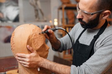 Craftsman carving wooden sculpture in workshop