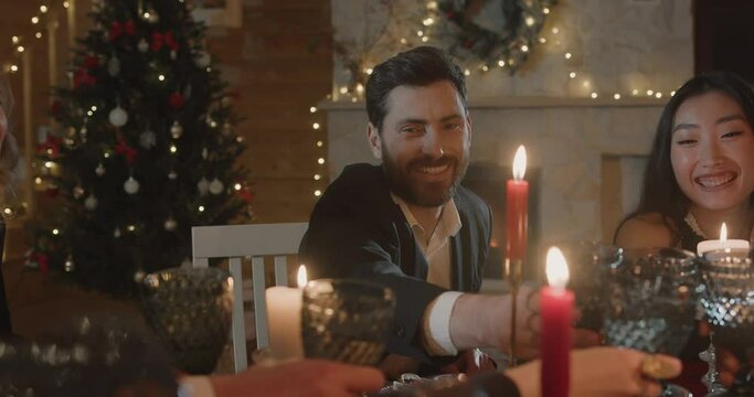  Friends in fashionable clothes  having Festive Dinner and Drinking, sitting in Decorated with lights Restaurant