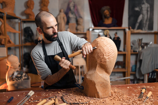 Focused craftsman shaping wooden detail with chisel