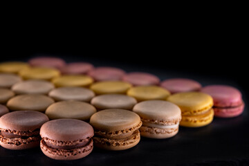 Obraz na płótnie Canvas chocolate, coffee, vanilla, lemon and strawberry macaroons on black background