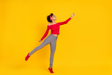 Obraz premium Photo of inspired dreamy lady stand tiptoe hold empty space wear pin-up outfit shiny pants isolated yellow color background