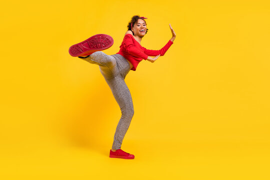 Photo Of Sporty Energetic Lady Leg Hit Camera Show Sole Wear Pin-up Outfit Shiny Pants Isolated Yellow Color Background