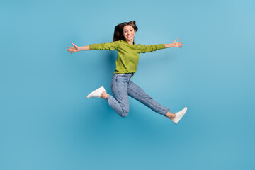 Fototapeta na wymiar Photo of pretty cheerful lady jump hurry run open hands wear green shirt jeans footwear isolated blue color background